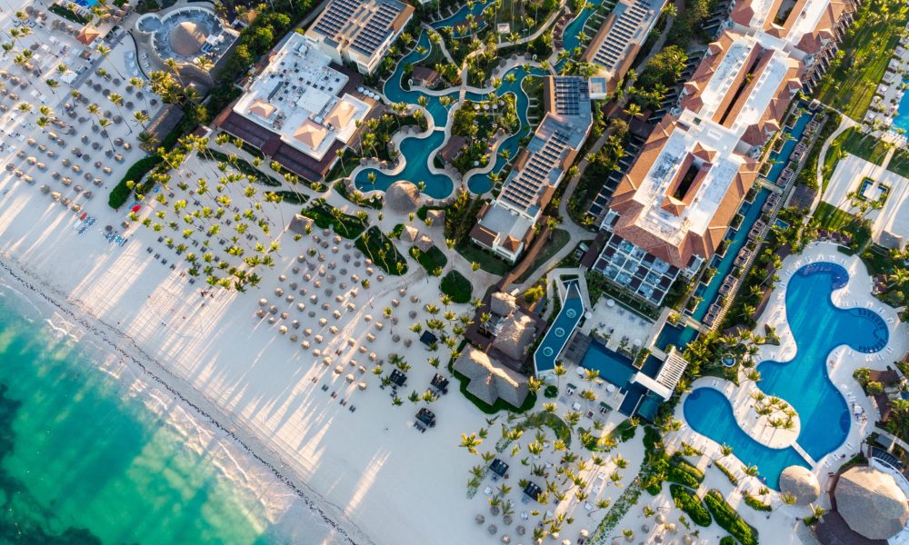 Aerial drone view of beach resort hotels with pools, umbrellas a